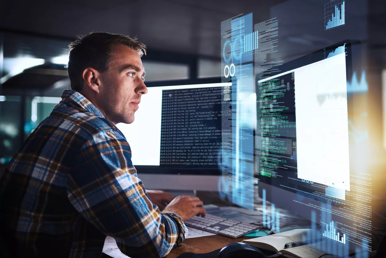 Shot of a young programmer working at his computer with an overlay of computer graphics while researching NAICS 541519 codes