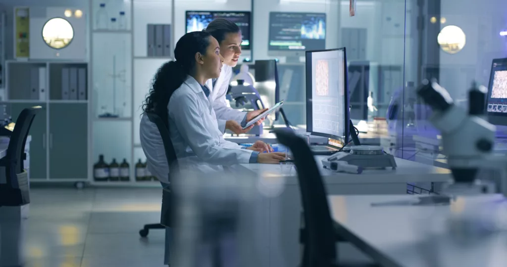 Medical researchers looking at and examining a brain scan on a computer while working late in an office together to demonstrate NAICS 541990 code.