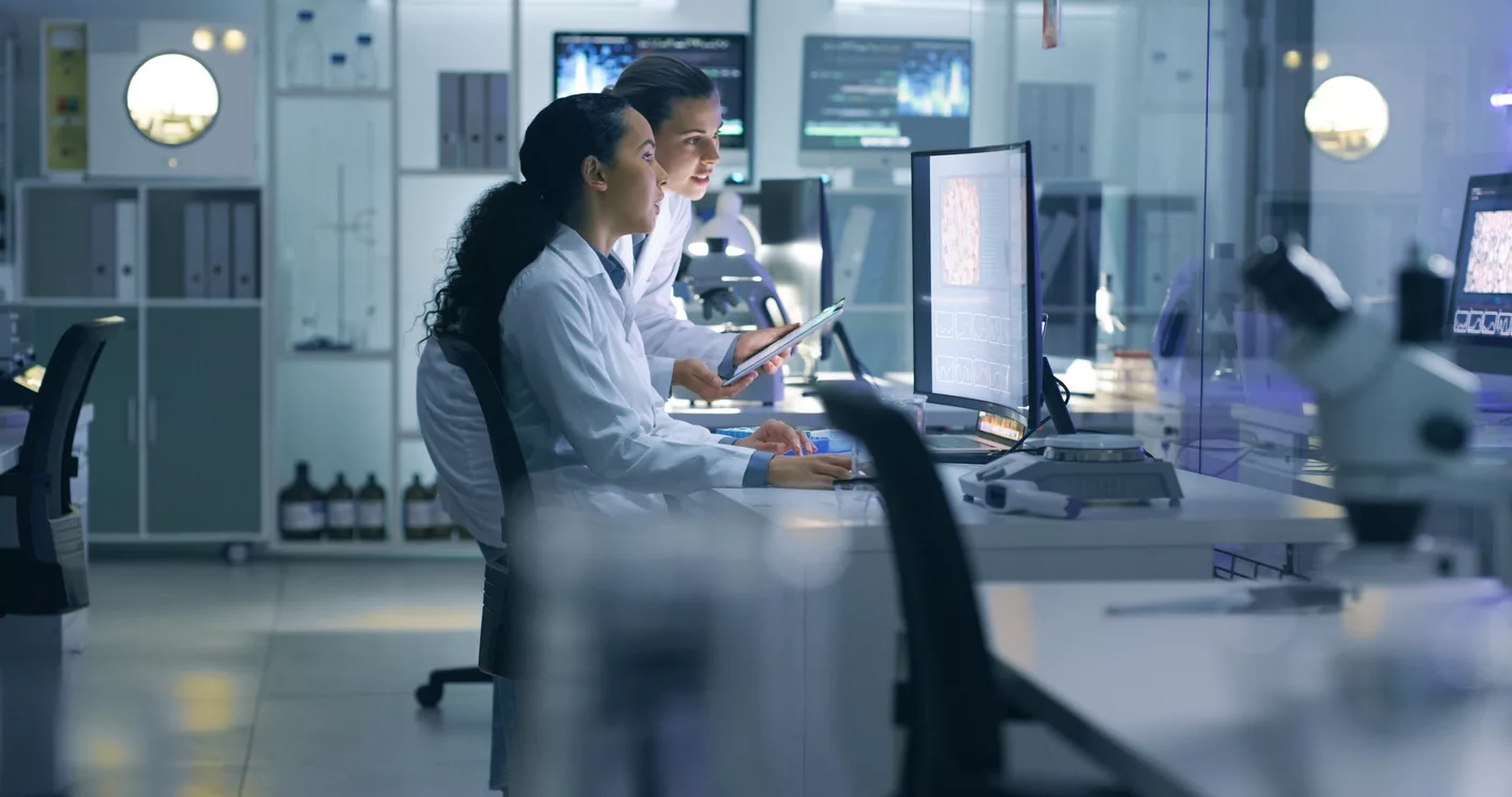 Medical researchers looking at and examining a brain scan on a computer while working late in an office together to demonstrate NAICS 541990 code.